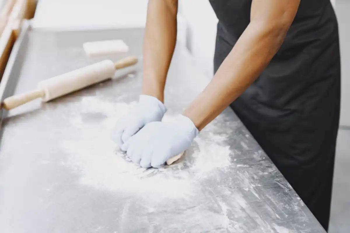 Bakker bewerkt deeg op een met bloem bestoven werkblad.