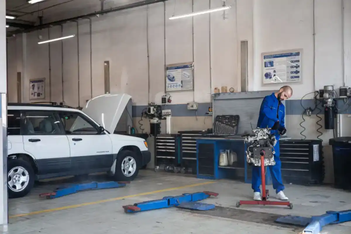 Monteur werkt aan een motor op een standaard in een autowerkplaats.