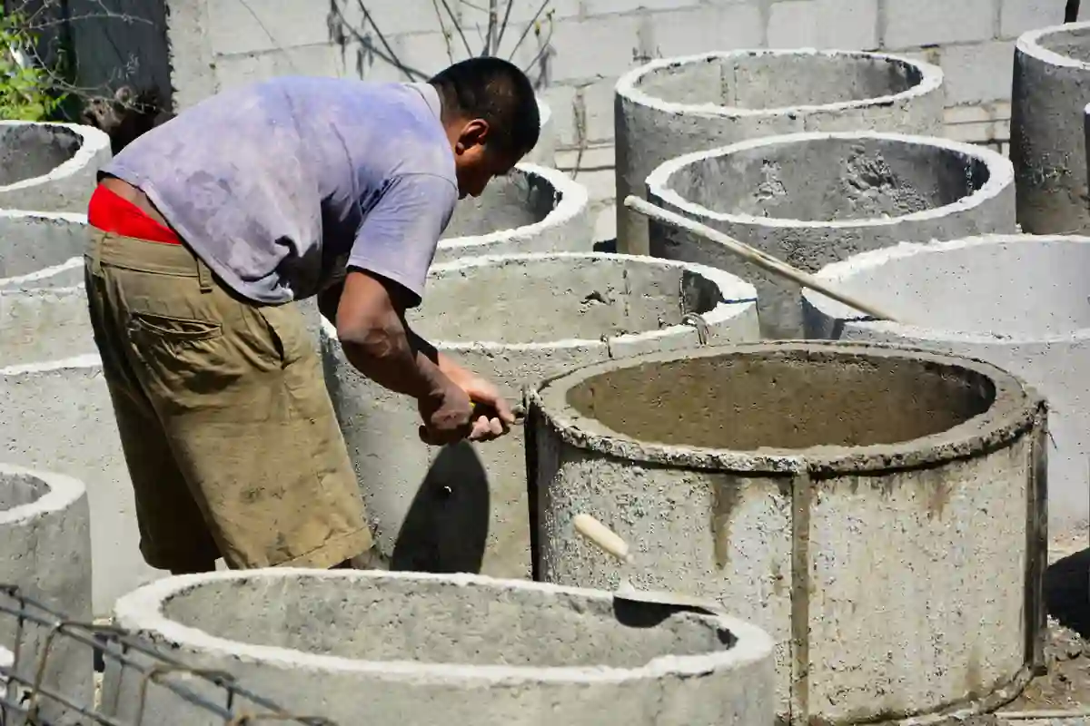 Een medewerker werkt met handgereedschap aan de rand van een betonnen ring.