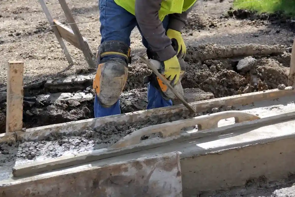 Medewerker werkt vers beton af met handgereedschap.
