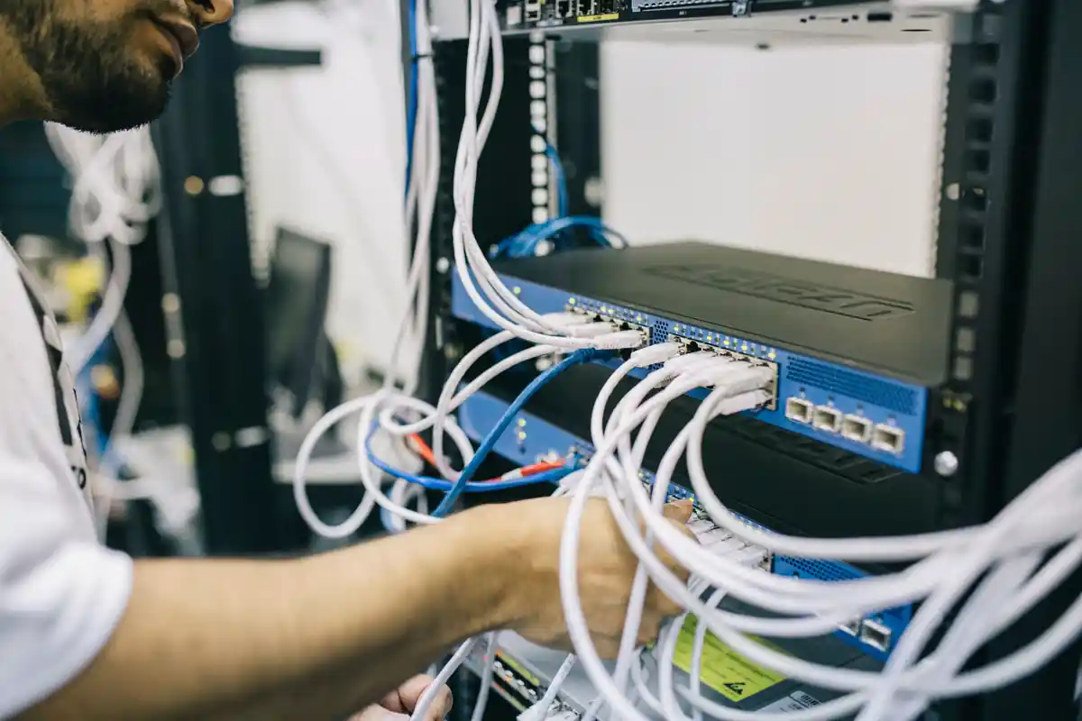 Een medewerker werkt aan netwerkkabels bij een Ethernet-switch in een apparatuurkast.
