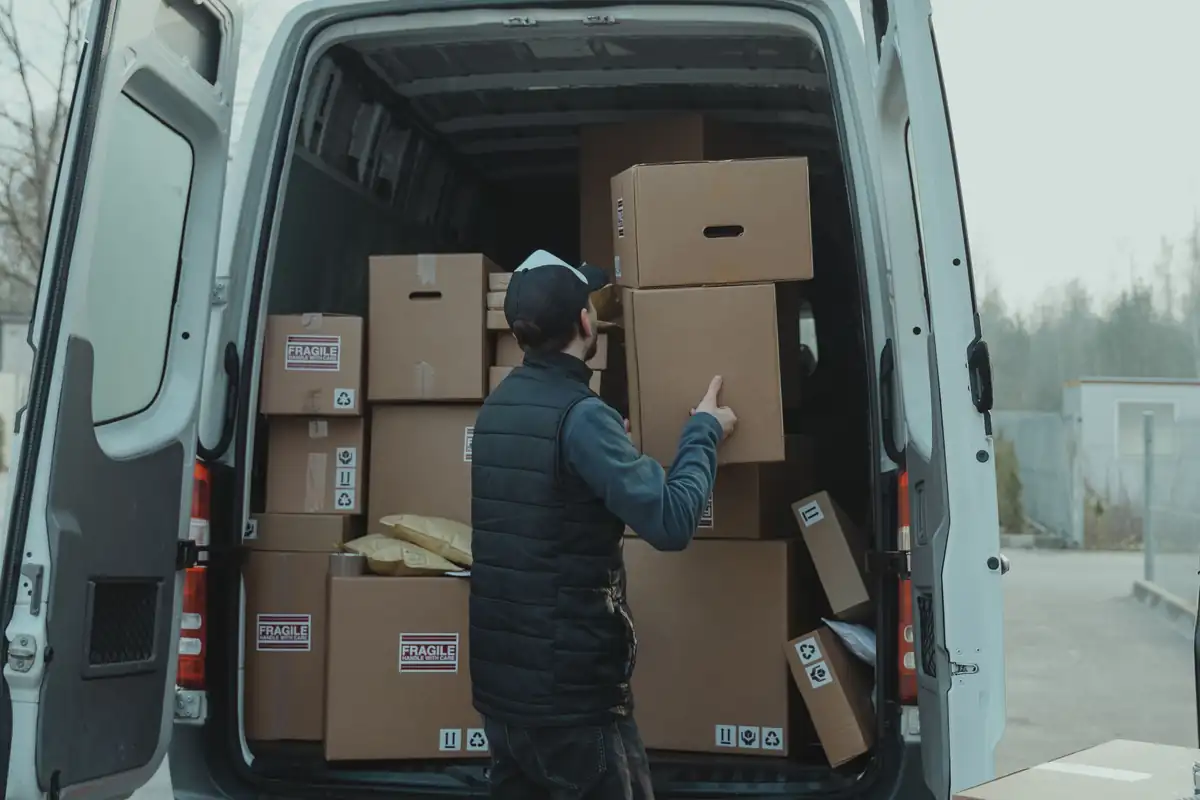 Een bezorger laadt kartonnen dozen in een bestelbus.