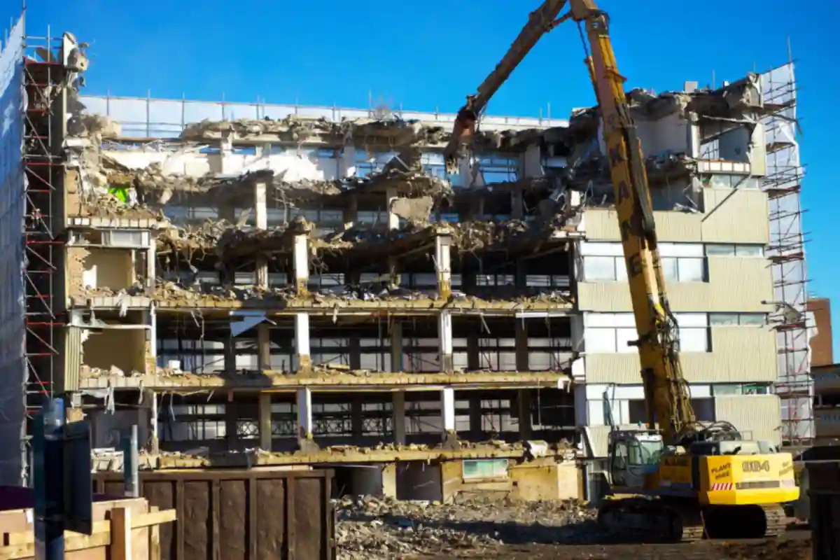 Graafmachine breekt een gebouw met betonnen verdiepingen af.