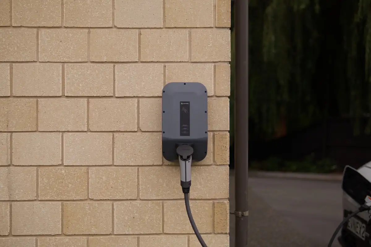 Een laadpunt voor elektrische voertuigen hangt aan een gemetselde buitenmuur.