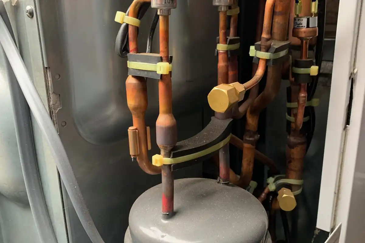 Koperen leidingen en technische onderdelen binnen de buitenunit van een warmtepomp.