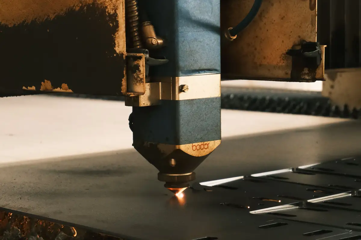 De snijkop van een lasersnijmachine snijdt een metalen plaat.