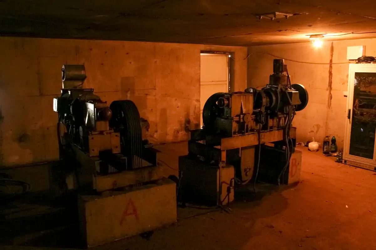 Machinekamer van een lift met elektromotoren en kabelschijven.