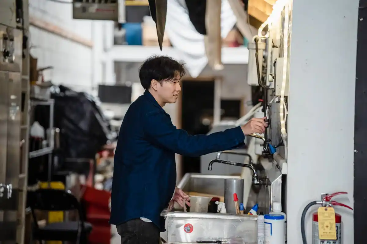 Medewerker bedient een grote machine in een fabriek.