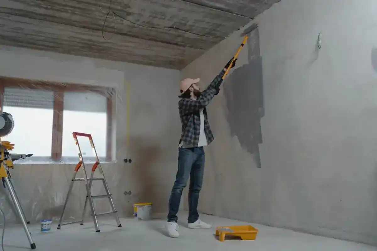Schilder brengt met een verfroller verf aan op een binnenmuur.