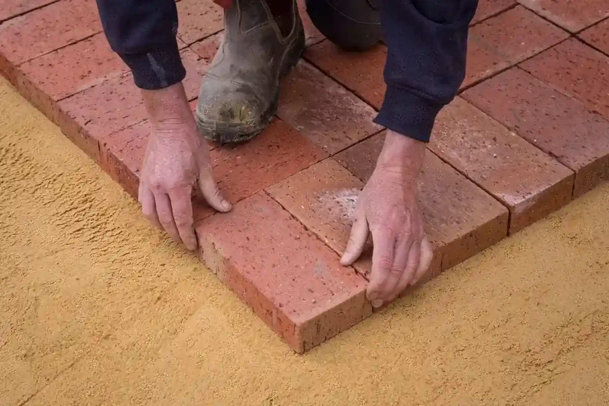 Stratenmaker legt klinkers op een zandbed.