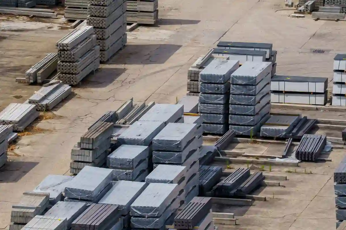 Betonnen prefab elementen liggen gestapeld op een opslagterrein.
