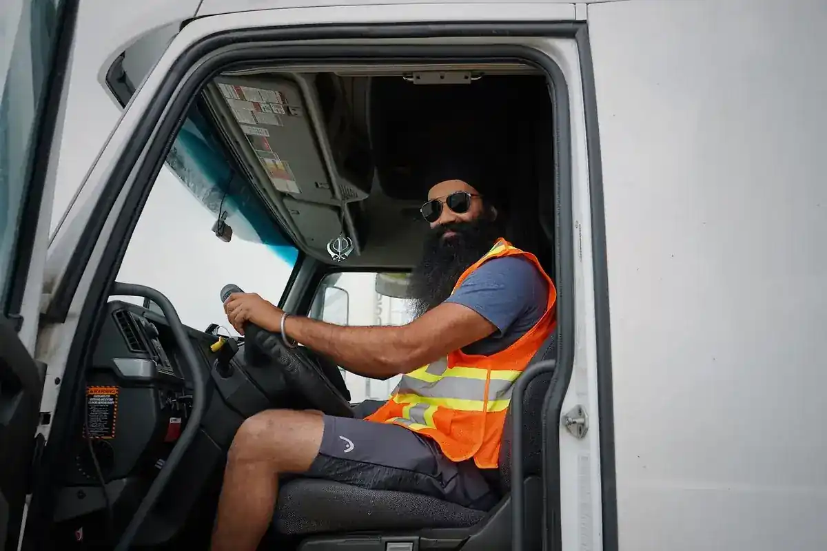 Chauffeur met reflecterend vest in de cabine van een vrachtwagen.