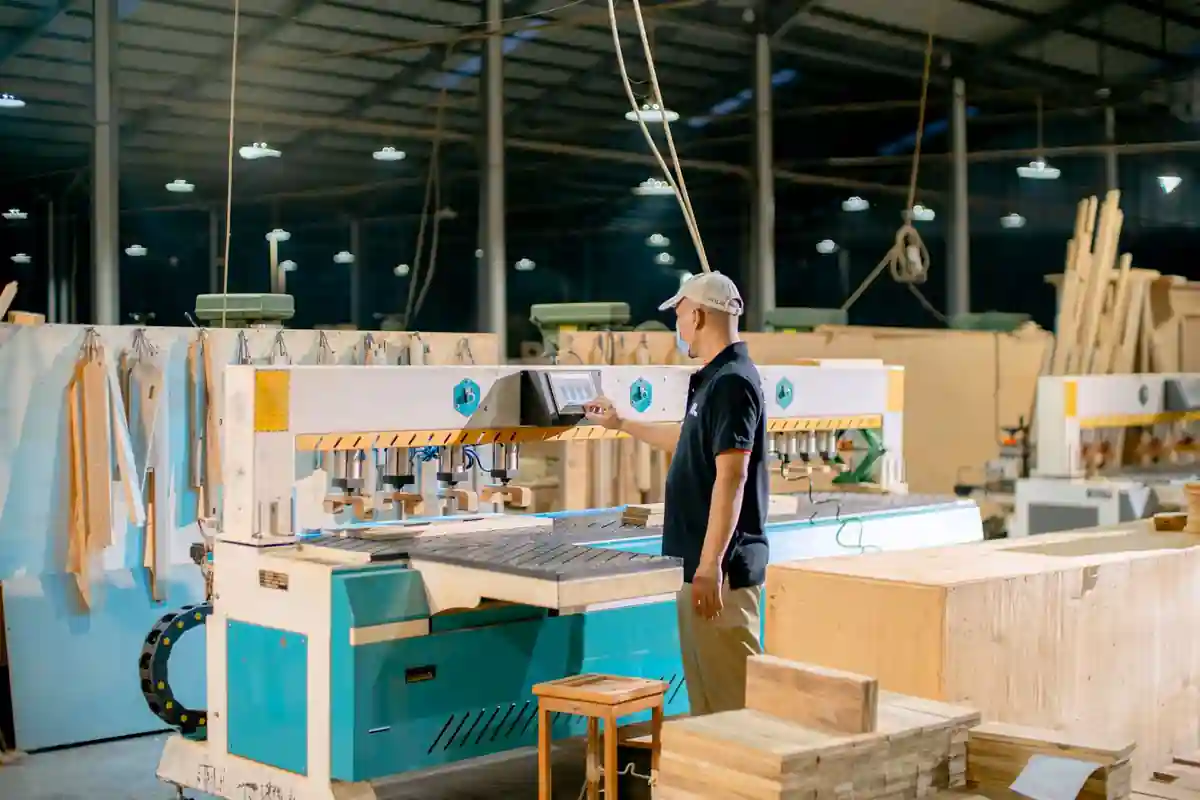 Medewerker staat bij een grote houtbewerkingsmachine in een werkplaats.